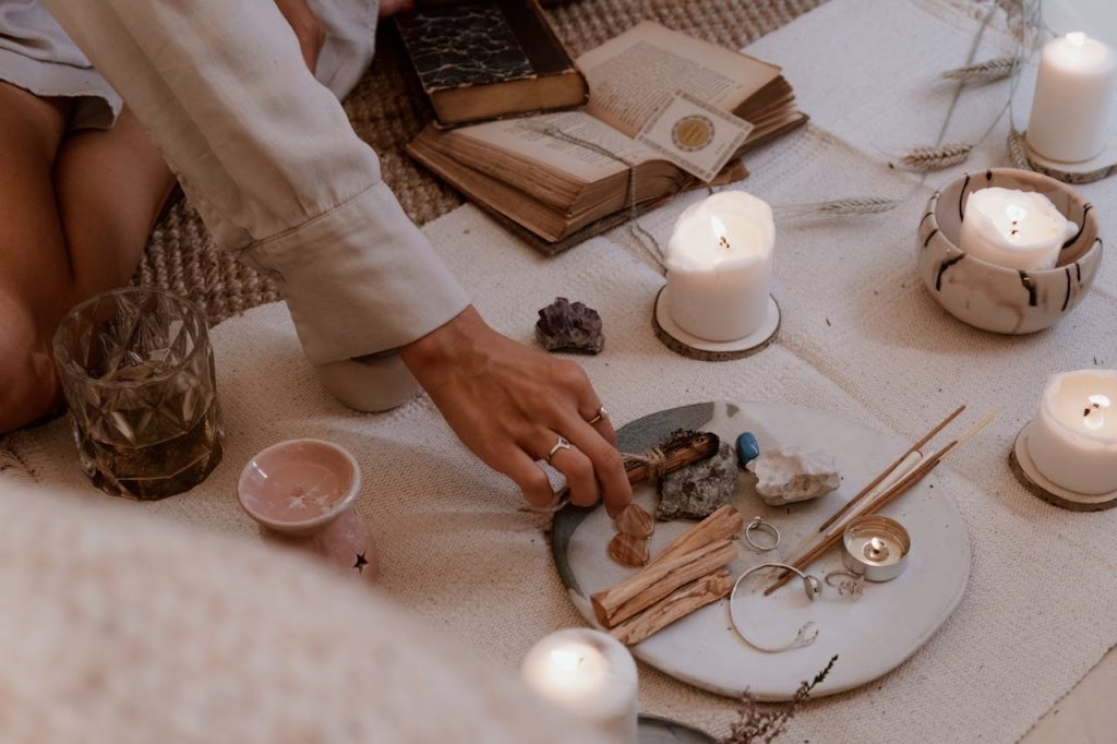 A peaceful ritual scene with candles, crystals, and incense sticks on a wooden table.